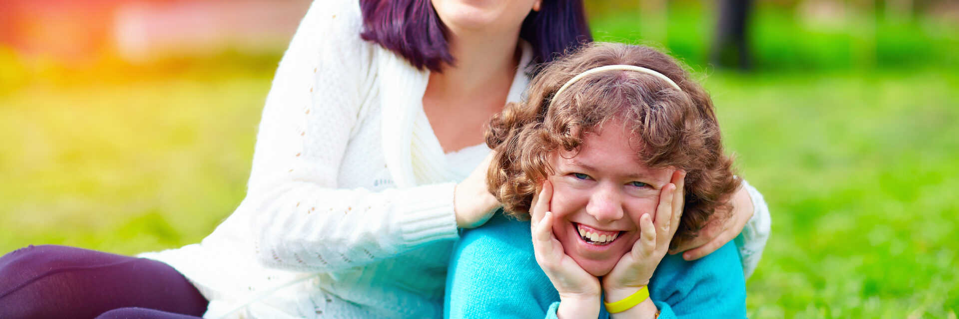 Two girls sitting on the grass smiling at the camera